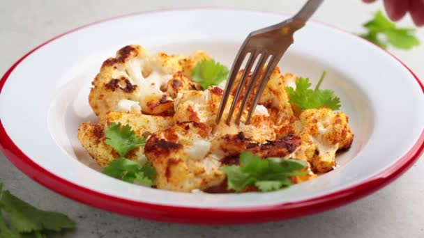 Chou-fleur épicé cuit au four avec du fromage feta dans une assiette blanche. — Video