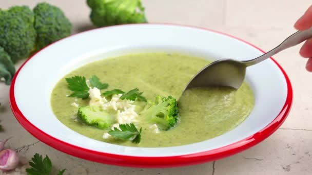 Суп из брокколи с сыром фета в тарелке на сером фоне плитки — стоковое видео