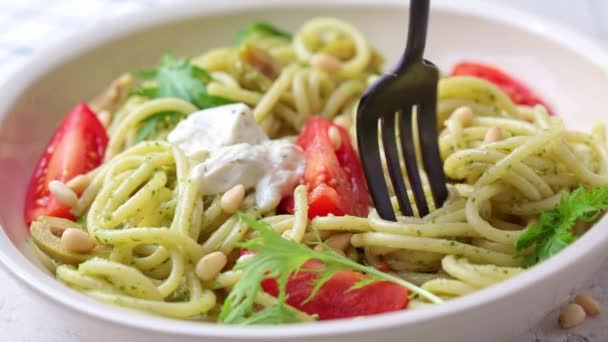 Pasta de espaguetis con salsa de pesto, aceitunas, tomates y piñones en tazón blanco. — Vídeo de stock