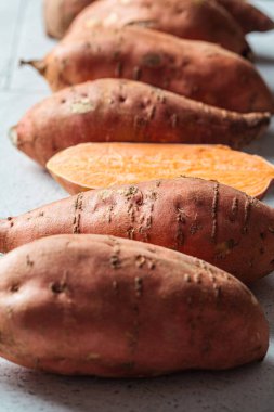 Çiğ pişmemiş tatlı patates, gri fayanslı arka planda, yakın plan..