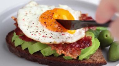 Avokadolu tost, kızarmış pastırma ve tabakta yumurta. Düşük karbonhidratlı keto diyeti. 