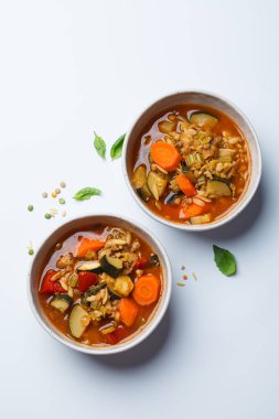 Vegetarian bean tomato soup with vegetables on a white background, top view.
