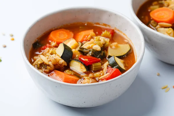 Vegetarian bean tomato soup with vegetables on a white background.