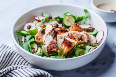 Izgara somon, salatalık, turp, kapari, roka ve tahini soslu salata..