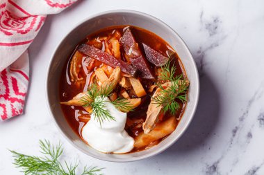 Masada gri bir kasede tavuklu ev yapımı borş çorbası..