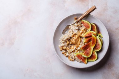 İncirli yulaf ezmesi, fıstık ezmesi, ceviz ve akçaağaç pekmezi, pembe mermer arka plan, üst manzara..