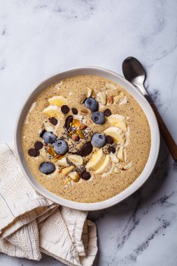 Muzlu, yaban mersinli ve fındıklı çikolatalı smoothie kasesi. Çikolatalı vegan sağlıklı tarif konsepti.