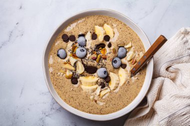 Muzlu, yaban mersinli ve fındıklı çikolatalı smoothie kasesi. Çikolatalı vegan sağlıklı tarif konsepti.