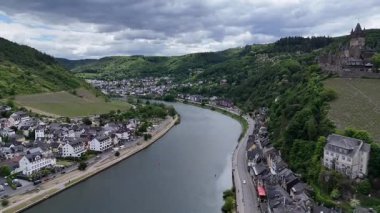 Nehir vadiyi saran Cochem kasabasının hava aracı görüntüleri, geleneksel evler, üzüm bağları, yeşil tepeler ve tarihi bir tepe şatosu.. 