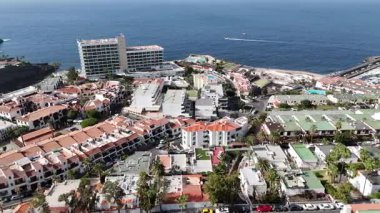 Los Gigantes 'in hava aracı görüntüleri kıyı yerleşim binalarını gösteriyor. Kırmızı kiremitli çatılar okyanus manzaralı oteller palmiye kaplı caddeler ve açık mavi bir günde açık mavi deniz..