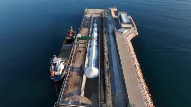 Kargo gemisinin endüstriyel deniz limanında deniz dalgakıranı sakin deniz ve deniz lojistiği olan beyaz tuzu boşaltırken insansız hava görüntüsü.
