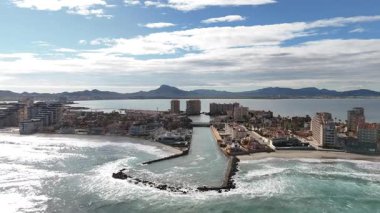 La Manga del Mar Menor 'un insansız hava aracı görüntüsü Akdeniz ile lagün, kıyı binaları, sahil, dalgalar ve İspanya' daki dağlar arasındaki kanalı gösteriyor.