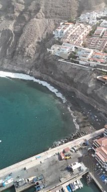 Los Gigantes kıyı köyünün insansız hava aracı görüntüsü dramatik volkanik kayalıkları Tenerife Kanarya Adaları 'ndaki okyanus ve plajı turkuaz hale getiriyor.