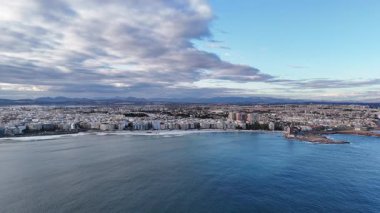 İspanya 'da dramatik bulutlu gökyüzü altında kentsel ufuk çizgisi kumlu sahil ve sakin Akdeniz ile Torrevieja şehir sahil şeridinin insansız hava görüntüsü