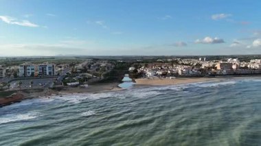 Kumlu sahili, deniz dalgaları ve kentsel alanı olan kıyı şehrinin insansız hava aracı görüntüsü. Yaz mevsimi deniz manzarası, kıyı şeridi, açık gökyüzü, gündüz seyahatleri..