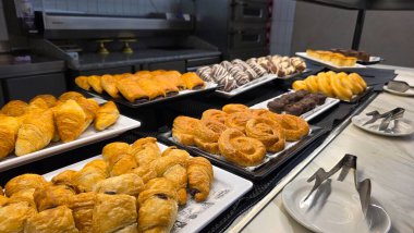 Otel kahvaltı büfesi fırında hamur işi kruvasan çikolatalı tatlılar ve modern self servis tezgahında servis edilen tatlı çörekler..