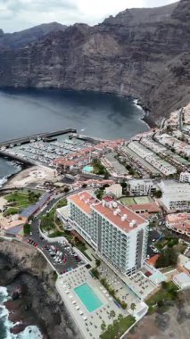 Deniz kıyısındaki tatil beldesinin insansız hava görüntüsü marina otelleri daireleri yüzme havuzu ve okyanus seyahati ve turizm konseptiyle dramatik uçurumlar.