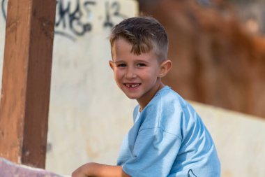 Mutlu gülümseyen çocuk gün ışığında dışarıda oturuyor ve fotokopi için fotokopi alanı olan doğal yaşam tarzı konseptine bakıyor.