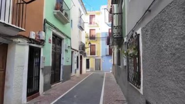 İspanyol eski kasabasında renkli evleri ve balkonları olan boş dar bir sokak, sakin bir yerleşim yeri, güneşli Akdeniz şehir mimarisi.