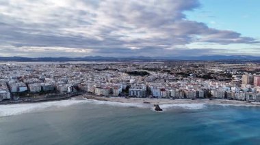 Torrevieja şehrinin kumsalı, kıyı şeridi ve Akdeniz 'i olan insansız hava aracı manzarası. Şehir silüeti, apartmanlar ve dalgalar dramatik bulutlu gökyüzü altında