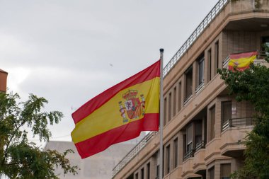 İspanya bayrağı iskan binasının önünde bayrak direğine sallanıyor. Ulusal sembol ve Avrupa ülkesi konsepti.