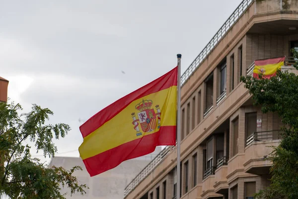 İspanya bayrağı iskan binasının önünde bayrak direğine sallanıyor. Ulusal sembol ve Avrupa ülkesi konsepti.