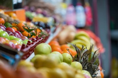 Açık hava pazarında el yazısıyla satılan ananas, mango ve elmalar dahil taze tropikal meyveler.