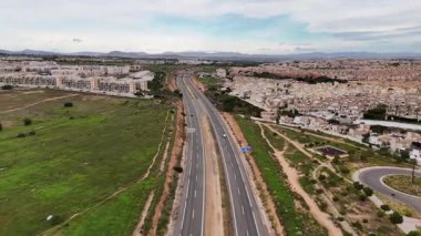 Ufukta yeşil alanlar ve dağlarla yoğun konut bölgesi yakınlarındaki çoklu yol üzerinde uçan insansız hava aracı kentsel kalkınma ve ulaşım altyapısı kavramı