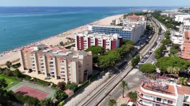Güneşli bir yaz gününde Katalonya 'da kumlu sahil, oteller, demiryolu hattı ve Akdeniz ile Malgrat de Mar sahilinin insansız hava aracı panoraması.