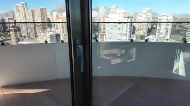 Elle açılan sürgülü balkon kapısını, modern şehir ufuk çizgisi manzarasıyla kapatın. Gayrimenkul, apartman ve mülk kavramı.