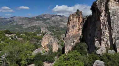 İspanya 'nın Guadalest şehrinde mavi gökyüzü altında yeşil vadi ve Akdeniz doğası ile dramatik kayalık kayalıkların ve dağ manzaralarının insansız hava görüntüsü.