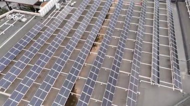 Büyük endüstriyel çatılara kurulmuş güneş paneli sisteminin insansız hava görüntüsü. Yenilenebilir enerji üretimi ve sürdürülebilir güç kavramı.