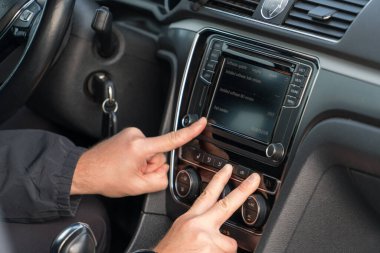 Sürücünün araba multimedya dokunmatik ekranı ve klima kontrol paneliyle etkileşimini kapat. Modern araç teknolojisi ve akıllı ulaşım konsepti.