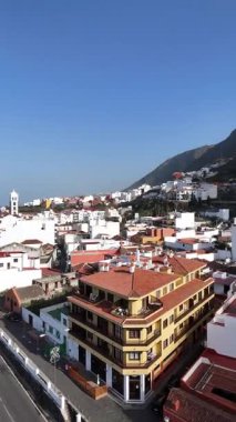 Beyaz evleri, kırmızı çatıları ve volkanik dağın yanındaki kilise kulesi olan geleneksel İspanyol kasabasının hava manzarası. Kanarya Adaları mimarisi ve caddelerinin manzarası.