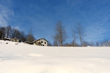 15 Aralık 2024, Trabzon, Türkiye Kış Sessizliği: Karlı HillA 'daki eski ev, karla kaplı bir yamaçta, canlı mavi bir gökyüzünün altında, kışın dinginliği ve kırsal huzuru çağrıştıran sessiz bir şekilde oturuyor..