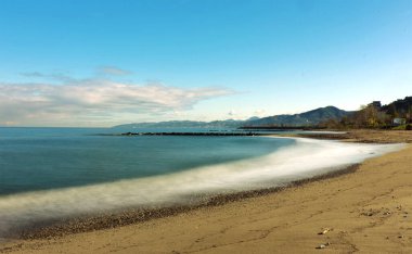 Pürüzsüz deniz yüzeyi ve kumlu kıyı şeridi olan minimalist sahil manzarası uzun süre korunuyor. Fotokopi alanı olan huzurlu sahil manzarası, seyahat, sağlık, yaz ve doğa arka plan kavramları için ideal