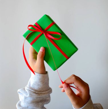 Yeşil hediye kutusu ve insan ellerinde kırmızı bir fiyonk. Yüksek kalite fotoğraf