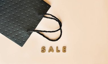 Bej arka planda siyah bir çanta ve satılık bir yazı. Yüksek kalite fotoğraf