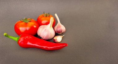 Gri arka planda domates, biber ve sarımsak kompozisyonu, metin için üst görüş alanı. Yüksek kalite fotoğraf