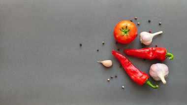 Gri arka planda domates, biber ve sarımsak kompozisyonu, metin için üst görüş alanı. Yüksek kalite fotoğraf