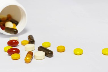 Beyaz arka planda beyaz bir şişeyle vitamin ve takviyelerin yakın plan fotoğrafı. Buna multi vitaminler, B vitamini, C vitamini, D vitamini, kolajen hapları, probiyotik kapsüller ve demir kapsüller dahil..