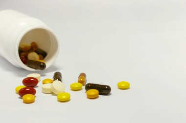 Beyaz arka planda beyaz bir şişeyle vitamin ve takviyelerin yakın plan fotoğrafı. Buna multi vitaminler, B vitamini, C vitamini, D vitamini, kolajen hapları, probiyotik kapsüller ve demir kapsüller dahil..