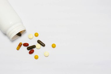 Beyaz arka planda beyaz bir şişeyle vitamin ve takviyelerin yakın plan fotoğrafı. Buna multi vitaminler, B vitamini, C vitamini, D vitamini, kolajen hapları, probiyotik kapsüller ve demir kapsüller dahil..