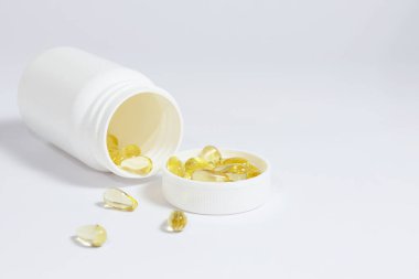 Beyaz arka planda beyaz bir şişeyle balık yağlarının yakın plan fotoğrafı..