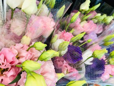 Çiçekçi tarafından satılan buketler arasında genellikle lisianthus veya prairie gentian olarak bilinen pembe, sarı ve beyaz Eustoma bulunmaktadır.,