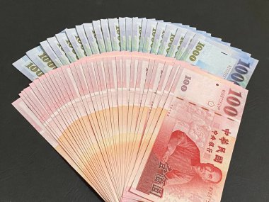 Siyah arka planda bin NT dolar ve yüz NT dolar. 1000 ve 100 Yeni Tayvan Doları.