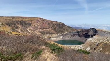 Okama Krateri Gölü güneşli bir günde. Yerel halk ona sevgiyle Okama derken, ziyaretçiler ona 