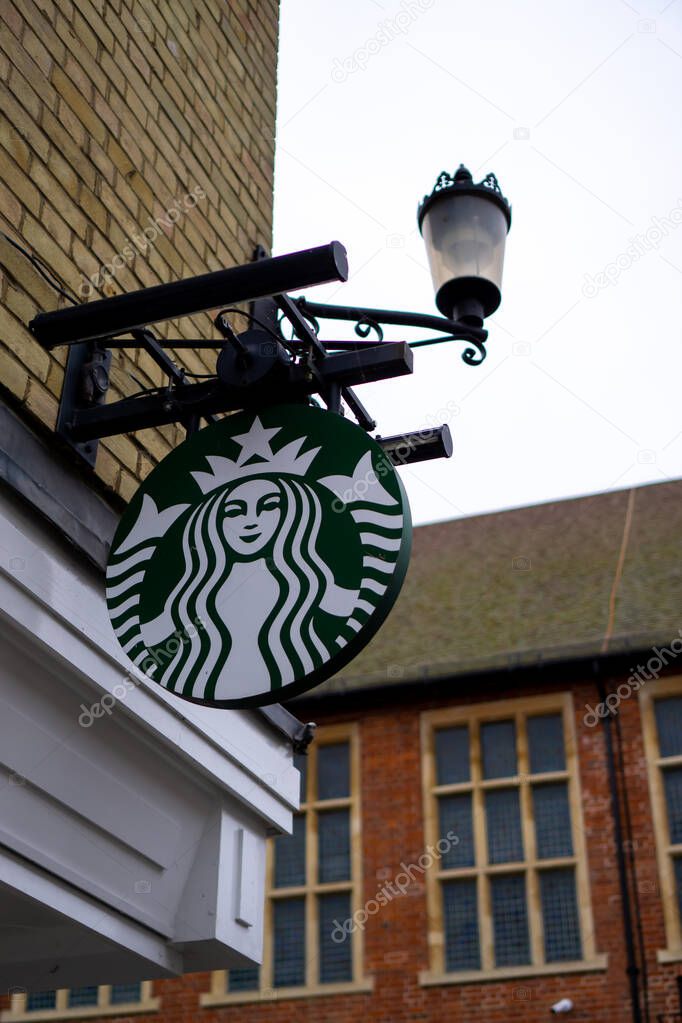 Saffron Walden, Essex, UK - January 12, 2024: Starbucks coffee shop hanging sign with old fashioned street light