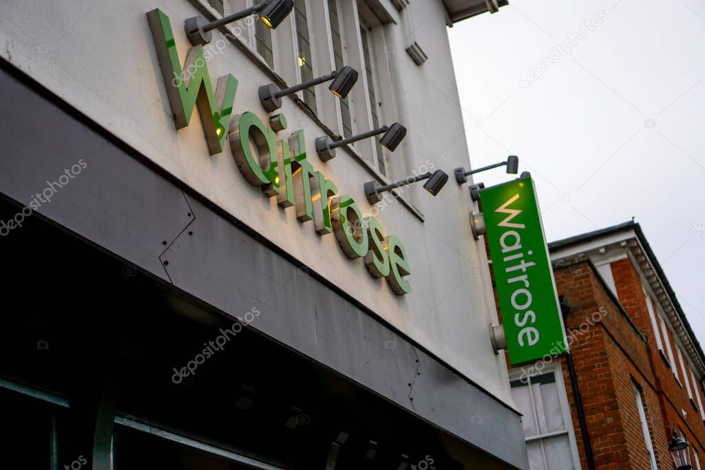 Saffron Walden, Essex, UK - January 12, 2024: Waitrose supermarket illuminated shop sign with additional vertical sign