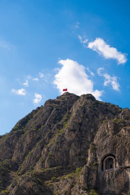 Castle in Amasya, Turkey. bottom view of turkey flag and blue sky above the mountain. It has changed hand and restored many times in the history during the Persian, Roman, Pontic and Byzantine era